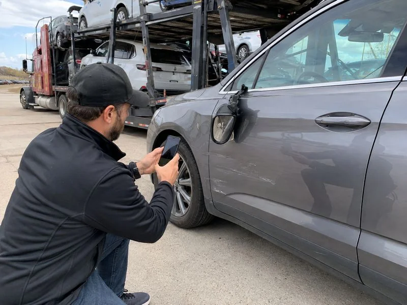Customer inspecting a delivered vehicle for freight damage and taking photos